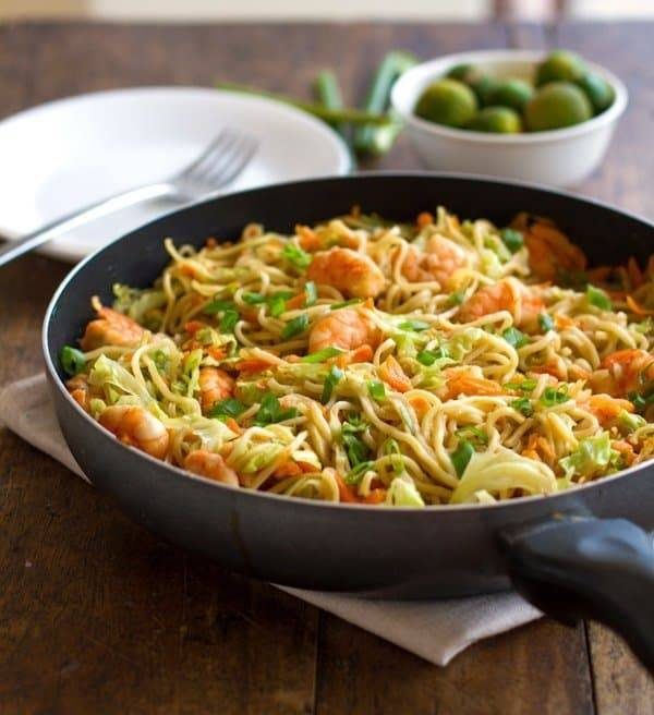 Stir fried noodles with shrimp and veggies in a skillet.