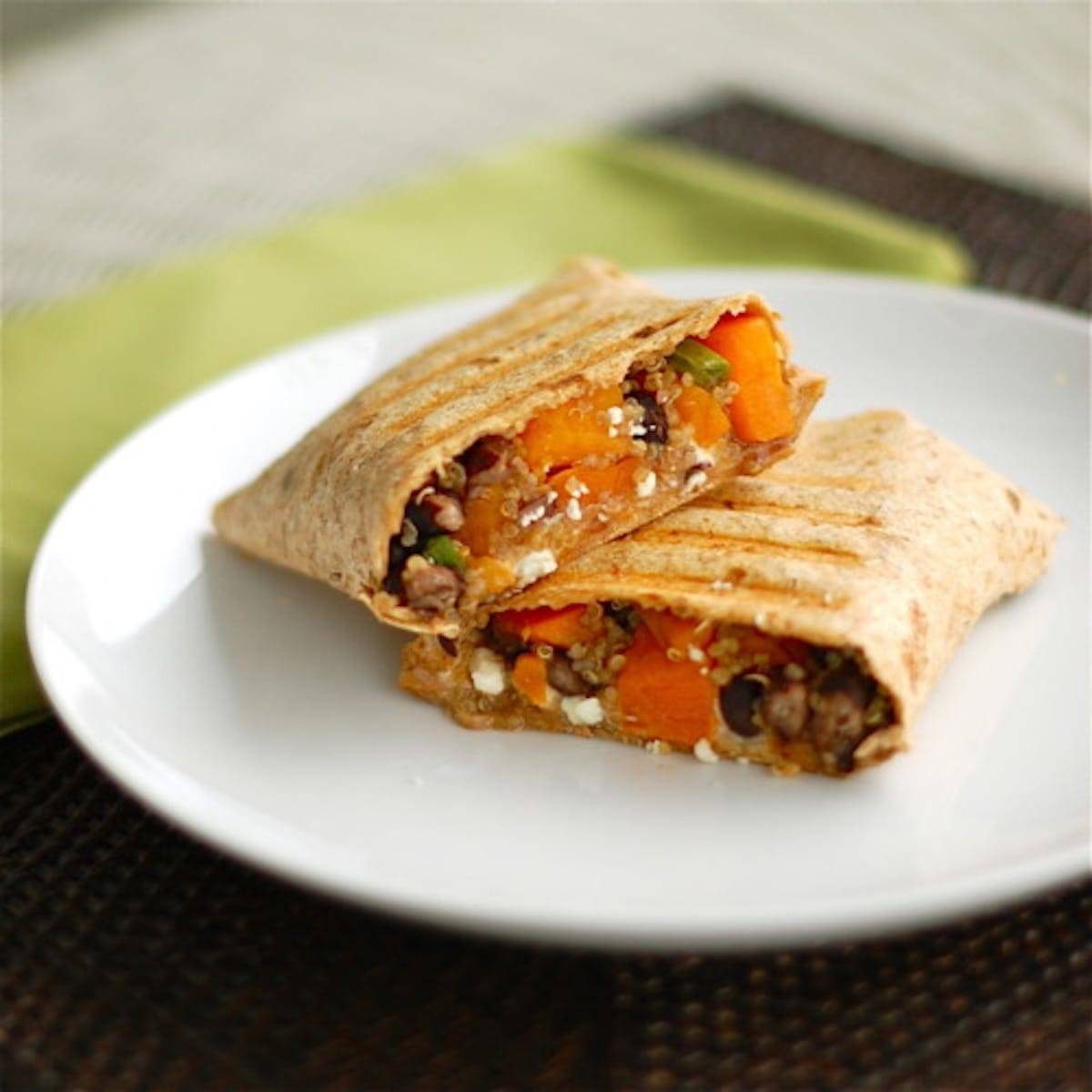 Butternut squash black bean wrap sliced down the center on a white plate.