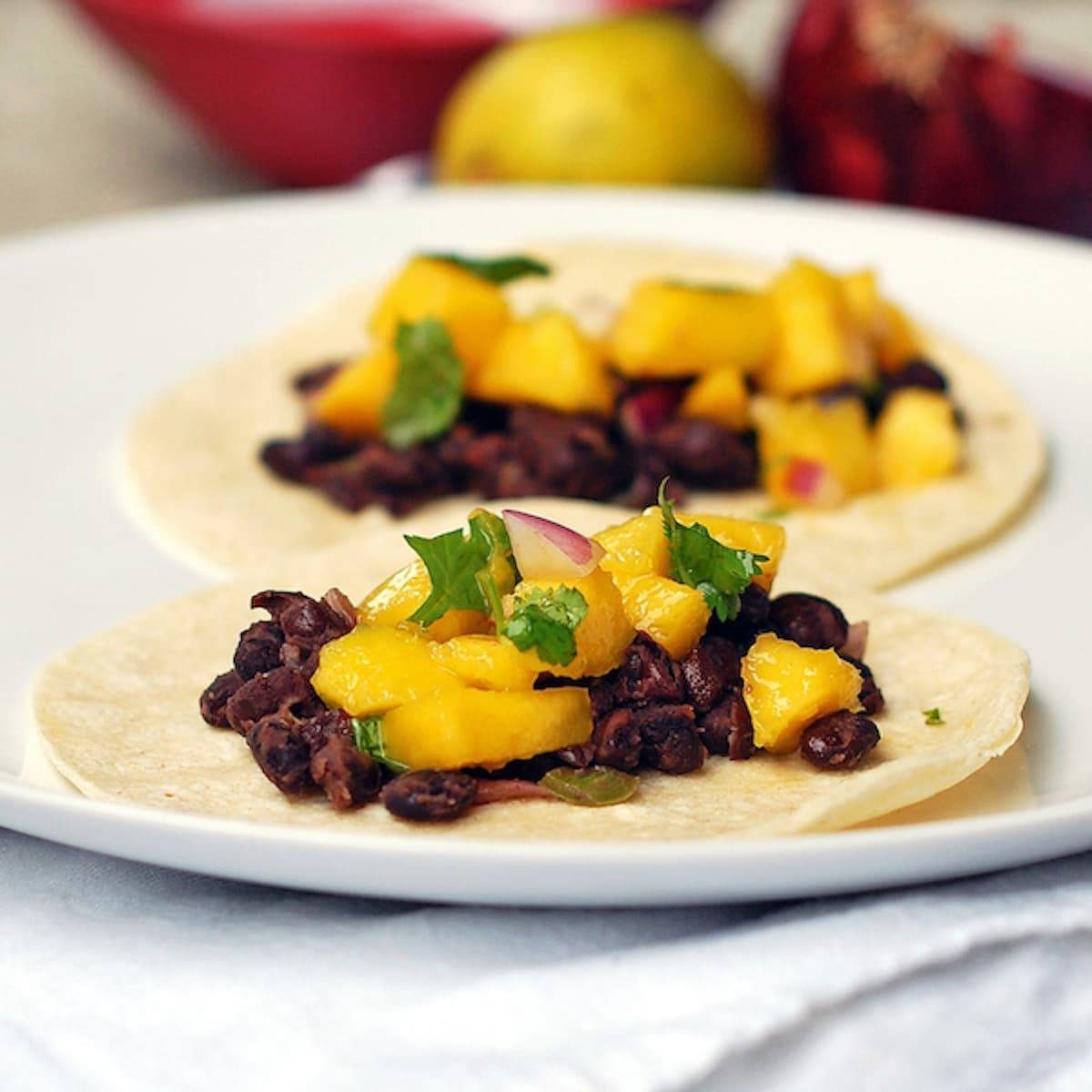 Mango black bean tacos with a creamy coconut sauce drizzled over the top.