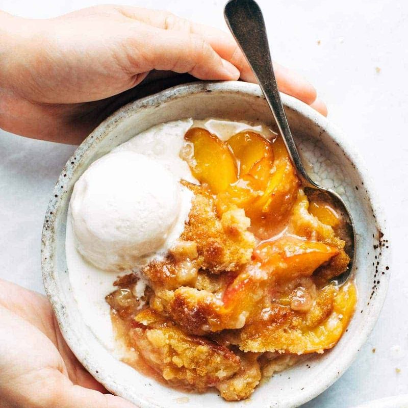 Peach cobbler in a bowl with ice cream.