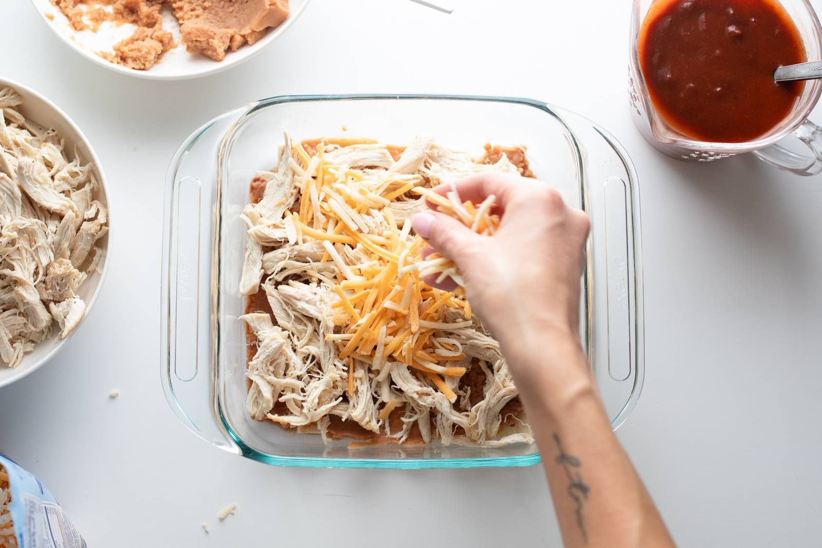 Sprinkling cheese on an enchilada casserole.