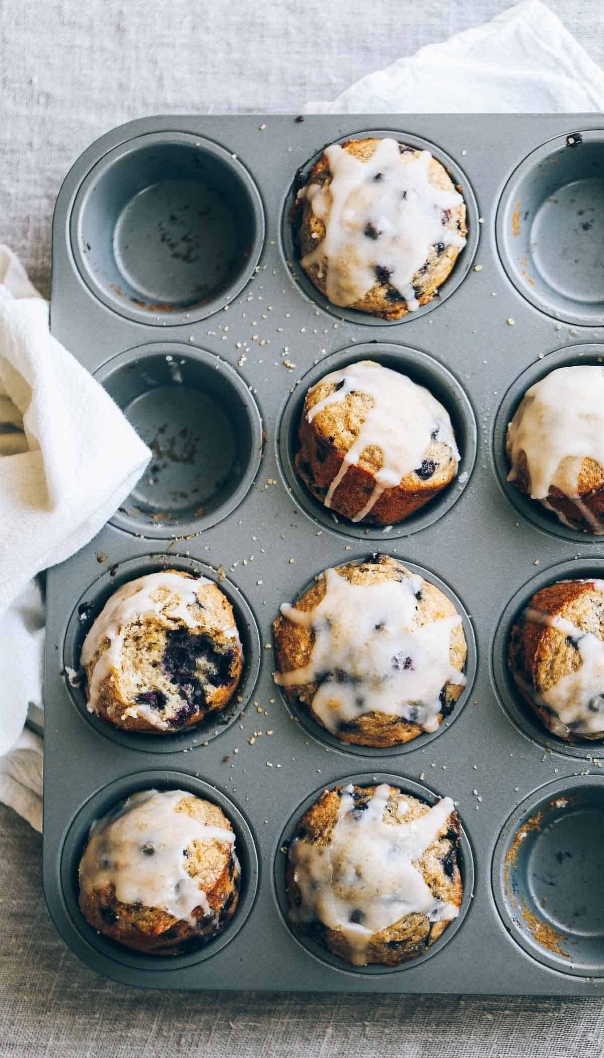 Whole Wheat Blueberry Muffins in a muffin tin with glaze.
