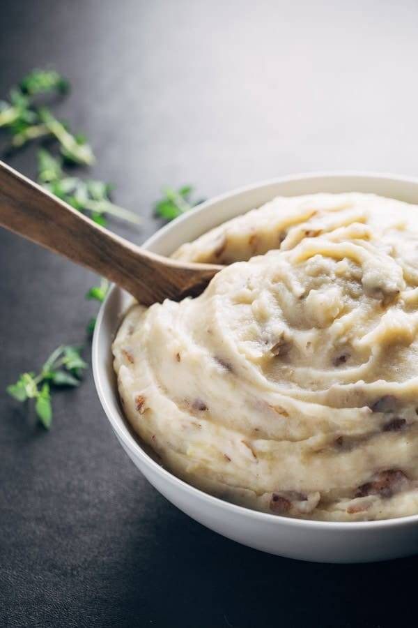 Mashed potatoes in a bowl with a wooden spoon.