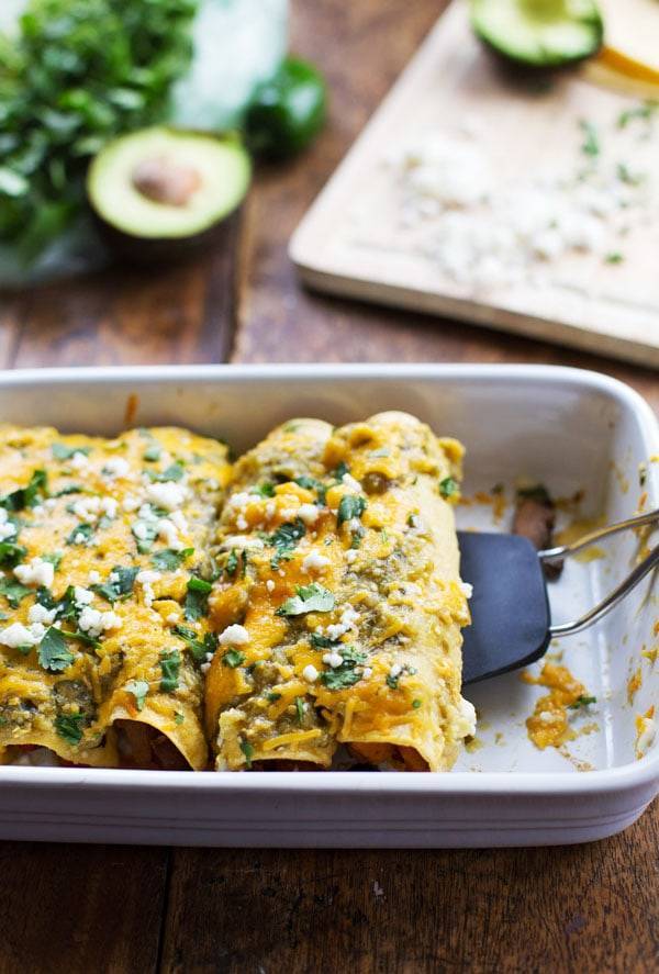 Butternut Squash and Mushroom Enchiladas with Tomatillo Sauce in a white baking dish.