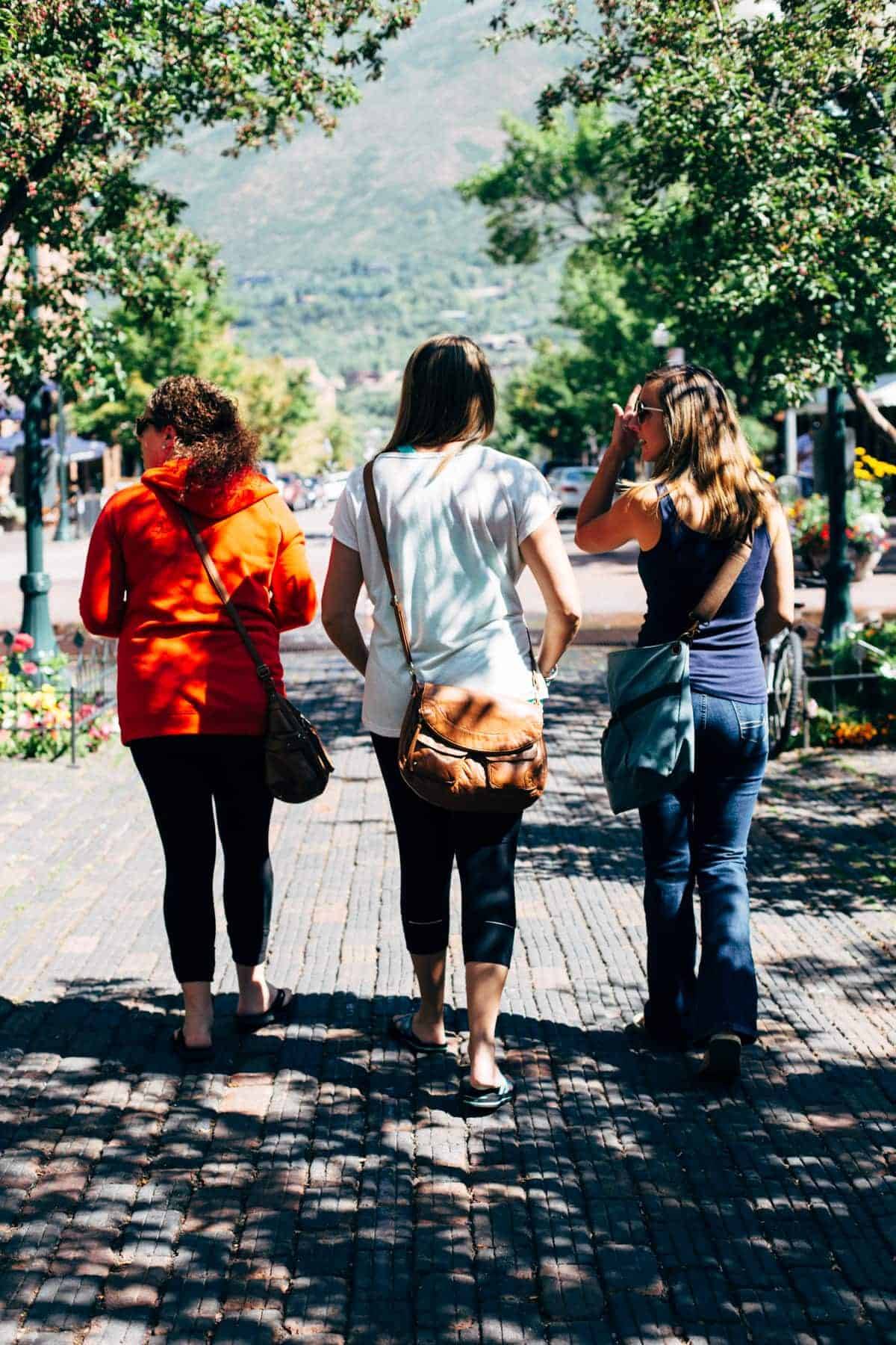 Three women walking on a sidewalk.