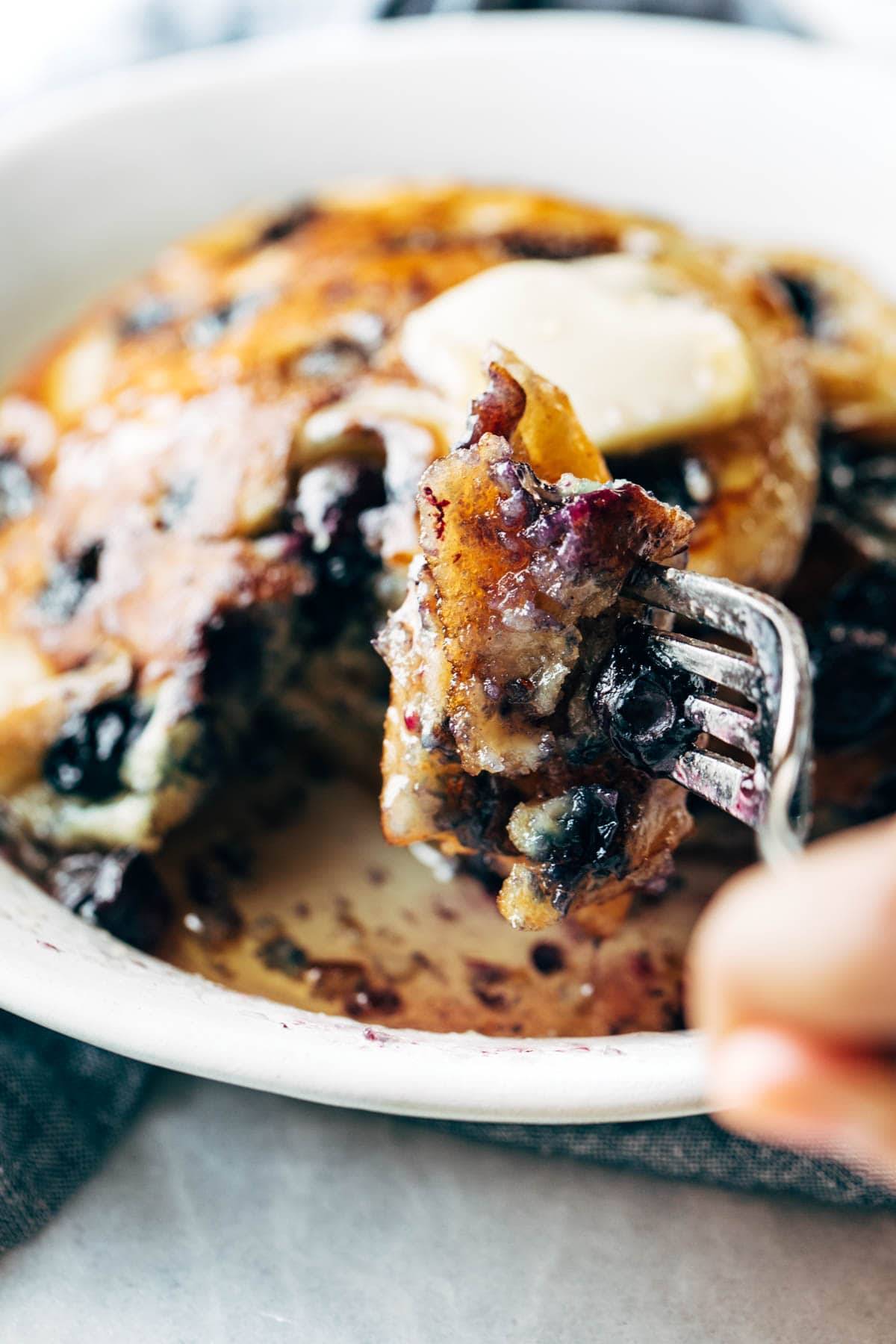 Bite of blueberry pancakes on a fork.