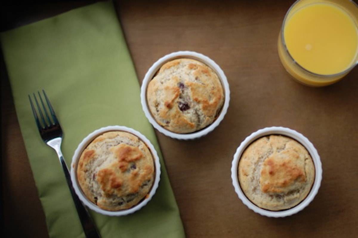Three dishes of strawberry breakfast cakes in white dishes on a green napkin with a fork and orange juice.