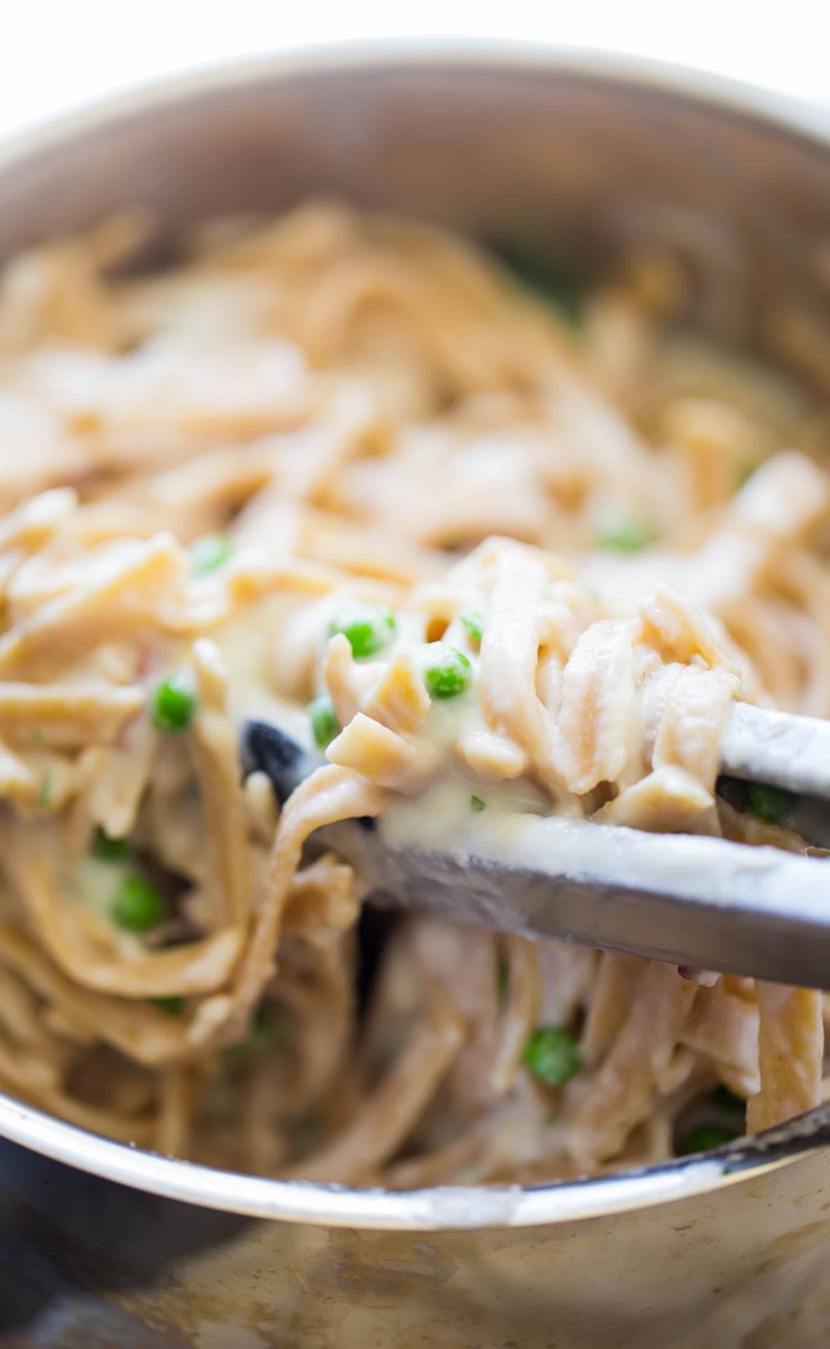 Whole Wheat Fettuccine Alfredo with tongs.